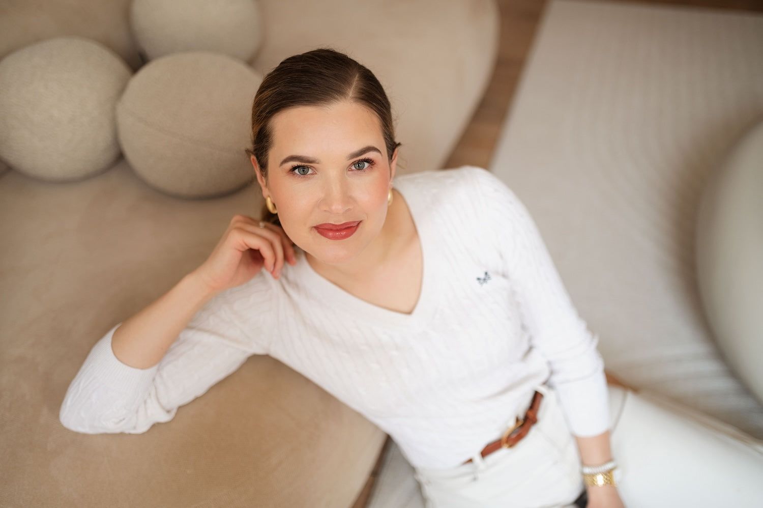 Kobieta w białym swetrze na kremowej sofie, sesja kobieca w Silky Studio